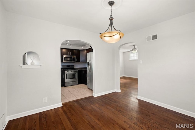 6915 Wise Ave, Saint Louis, MO 63139 - unfurnished dining area featuring wood finished floors, arched walkways, and a ceiling fan