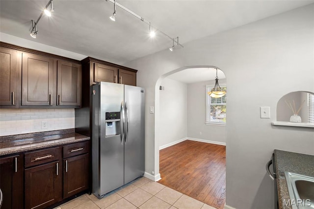 6915 Wise Ave, Saint Louis, MO 63139 - kitchen with stainless steel fridge, arched walkways, rail lighting, dark brown cabinets, and tasteful backsplash