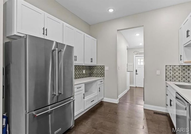 4355 Hunt Ave, Saint Louis, MO 63110 - kitchen featuring stainless steel appliances, light countertops, tasteful backsplash, dark wood-type flooring, and white cabinetry