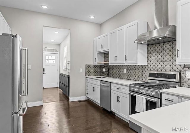 4355 Hunt Ave, Saint Louis, MO 63110 - kitchen with wall chimney range hood, appliances with stainless steel finishes, light countertops, white cabinets, and dark wood finished floors