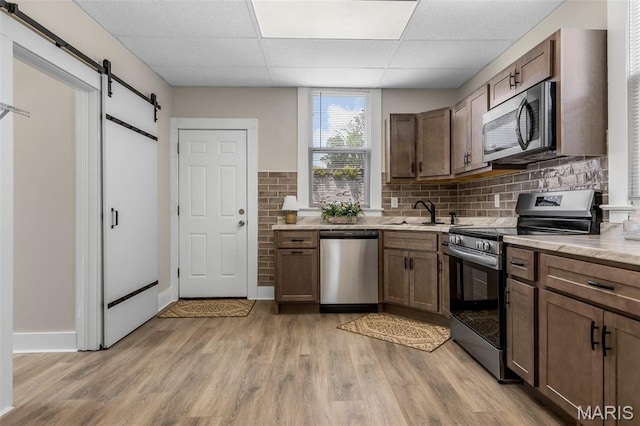 229 Broadway Ave, Crystal City, MO 63019 - kitchen with stainless steel appliances, a paneled ceiling, light wood finished floors, a barn door, and tasteful backsplash