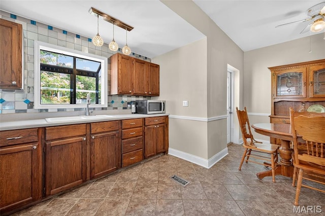 5965 S Cuba Ct, Saint Louis, MO 63139 - kitchen featuring stainless steel microwave, a ceiling fan, decorative backsplash, light countertops, and brown cabinets