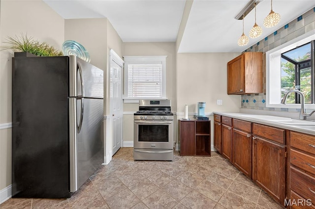 5965 S Cuba Ct, Saint Louis, MO 63139 - kitchen featuring stainless steel appliances, brown cabinets, light countertops, hanging light fixtures, and decorative backsplash