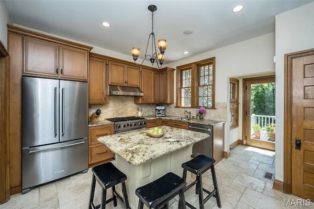 444 Algonquin Pl, Webster Groves, MO 63119 - kitchen featuring high quality appliances, under cabinet range hood, stone tile floors, recessed lighting, and a chandelier