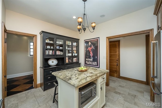 444 Algonquin Pl, Webster Groves, MO 63119 - kitchen featuring freestanding refrigerator, light stone finish floors, a chandelier, light stone countertops, and hanging light fixtures