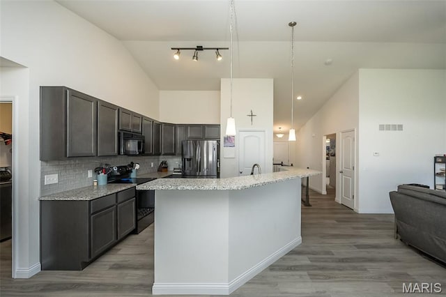 229 Essex Ct, Wright City, MO 63390 - kitchen featuring black appliances, high vaulted ceiling, light wood-type flooring, backsplash, and an island with sink