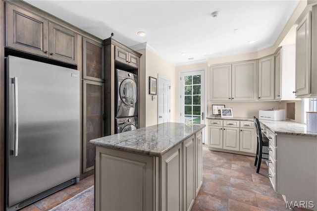 10420 Litzsinger Rd, Frontenac, MO 63131 - kitchen featuring high end refrigerator, stacked washer / drying machine, a kitchen island, light stone counters, and light stone finish flooring