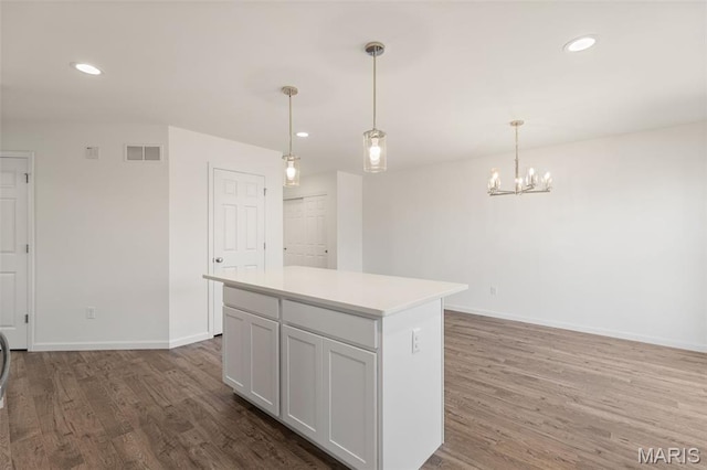 347 Heather Mill Dr, Wentzville, MO 63385 - kitchen with wood finished floors, light countertops, a chandelier, a kitchen island, and decorative light fixtures
