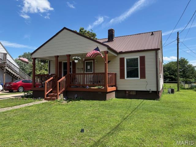 929 Lake St, Sikeston, MO 63801 - bungalow featuring covered porch, a chimney, a front lawn, and a metal roof