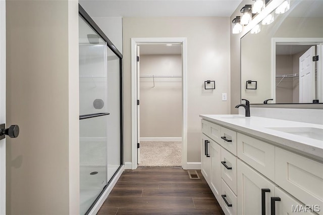 684 Fox Creek Dr, Fenton, MO 63026 - bathroom featuring wood finished floors, double vanity, a spacious closet, and a shower with shower door