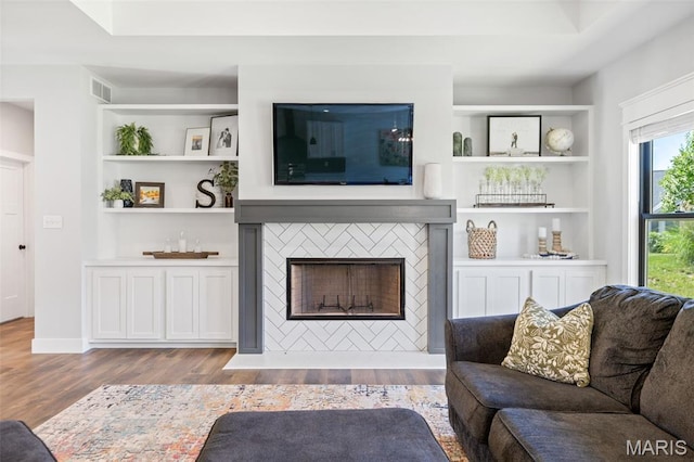 10523 Village Ln, Foristell, MO 63348 - living area with wood finished floors, a tiled fireplace, and built in features
