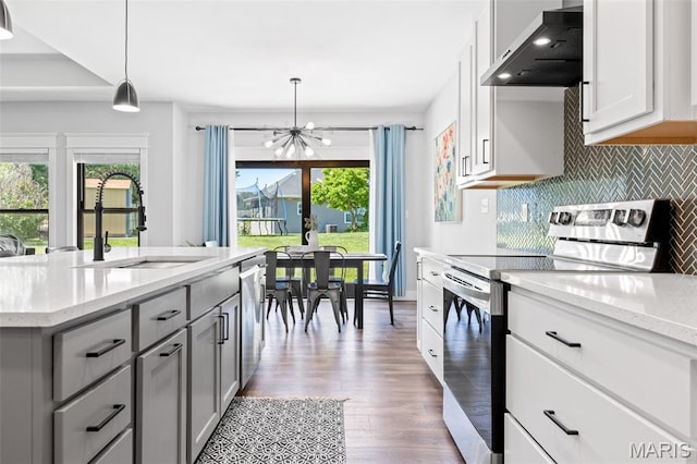 10523 Village Ln, Foristell, MO 63348 - kitchen featuring stainless steel appliances, wall chimney exhaust hood, a chandelier, gray cabinets, and backsplash