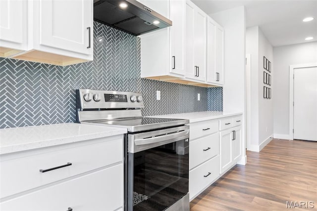 10523 Village Ln, Foristell, MO 63348 - kitchen with stainless steel range with electric stovetop, extractor fan, decorative backsplash, white cabinetry, and recessed lighting