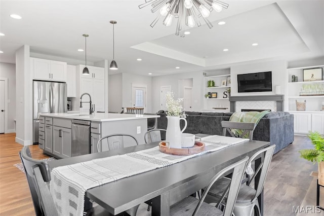 10523 Village Ln, Foristell, MO 63348 - dining space featuring a raised ceiling, recessed lighting, light wood-type flooring, and a chandelier