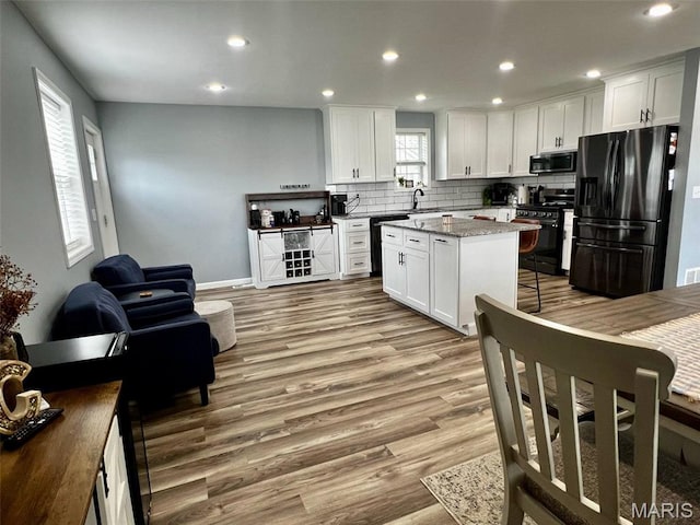 320 N Dickerson St, Palmyra, MO 63461 - kitchen featuring black appliances, light wood finished floors, a center island, white cabinetry, and recessed lighting