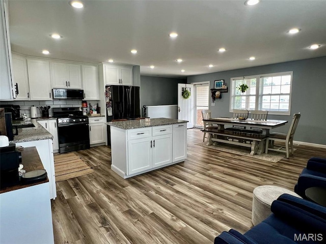 320 N Dickerson St, Palmyra, MO 63461 - kitchen with gas stove, black refrigerator with ice dispenser, a center island, recessed lighting, and dark wood-style flooring