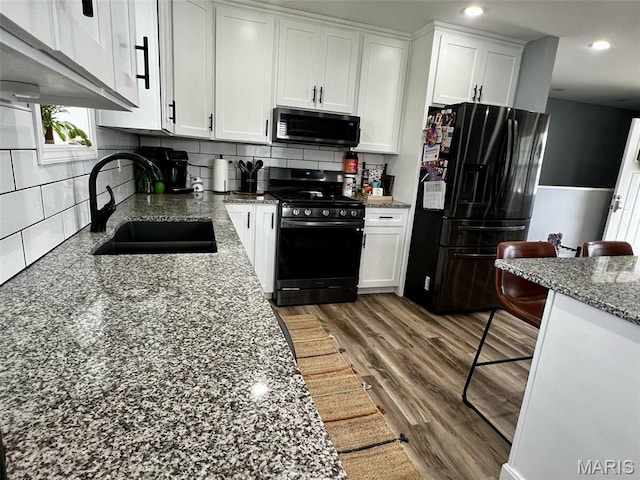 320 N Dickerson St, Palmyra, MO 63461 - kitchen featuring stainless steel gas range oven, black fridge with ice dispenser, white cabinetry, recessed lighting, and tasteful backsplash