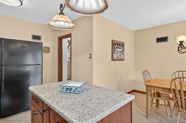 6580 Oleatha Ave, Saint Louis, MO 63139 - kitchen featuring freestanding refrigerator, light tile patterned floors, brown cabinets, a center island, and pendant lighting
