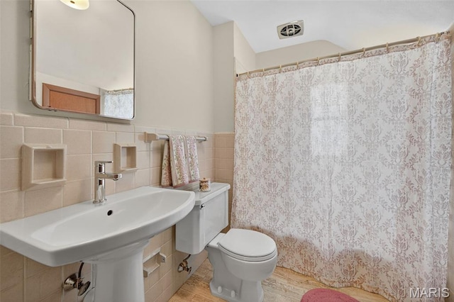 6580 Oleatha Ave, Saint Louis, MO 63139 - bathroom featuring tile walls, a shower with shower curtain, wood finished floors, and wainscoting