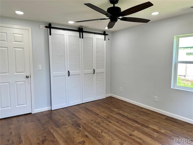 401 Clara St, Potosi, MO 63664 - unfurnished bedroom with a barn door, recessed lighting, dark wood-style flooring, ceiling fan, and a closet