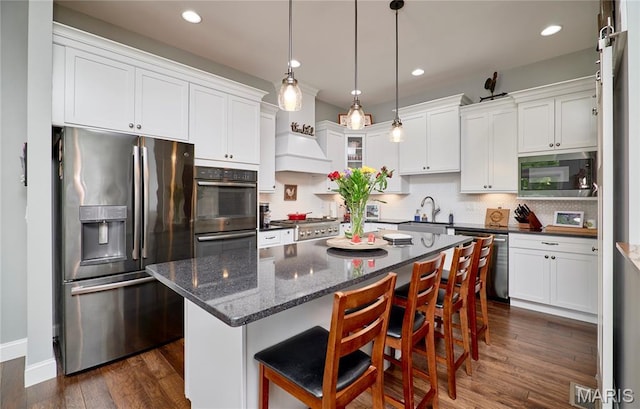 10234 Village Dr, Foristell, MO 63348 - kitchen featuring appliances with stainless steel finishes, white cabinetry, tasteful backsplash, and recessed lighting