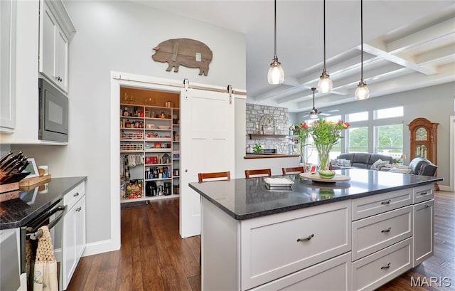 10234 Village Dr, Foristell, MO 63348 - kitchen featuring black microwave, a barn door, dark wood-type flooring, pendant lighting, and a ceiling fan