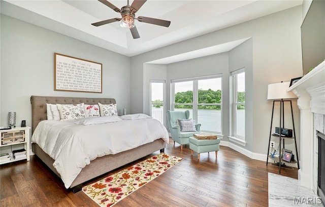 10234 Village Dr, Foristell, MO 63348 - bedroom featuring a premium fireplace, hardwood / wood-style flooring, a water view, and a ceiling fan