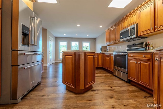 11782 Pine Forest Dr, Rolla, MO 65401 - kitchen featuring stainless steel appliances, brown cabinetry, wood finished floors, a kitchen island, and recessed lighting