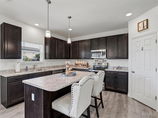 1673 Lake Meade Dr, Pacific, MO 63069 - kitchen featuring stainless steel appliances, light countertops, a breakfast bar, light wood-style flooring, and recessed lighting