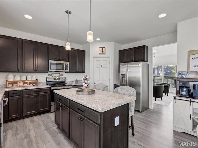 1673 Lake Meade Dr, Pacific, MO 63069 - kitchen with stainless steel appliances, a kitchen bar, a kitchen island, light countertops, and light wood-style flooring