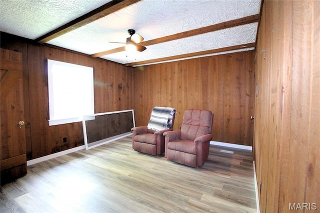 14525 Meadowlark Ln, Saint Genevieve, MO 63670 - sitting room featuring wooden walls, a ceiling fan, beamed ceiling, wood finished floors, and a textured ceiling