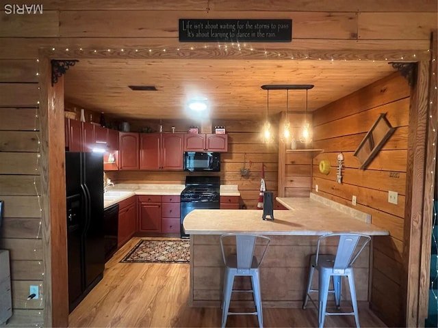 171 Bluffview Cir, Piedmont, MO 63957 - kitchen with black appliances, light wood finished floors, light countertops, wooden walls, and a kitchen breakfast bar