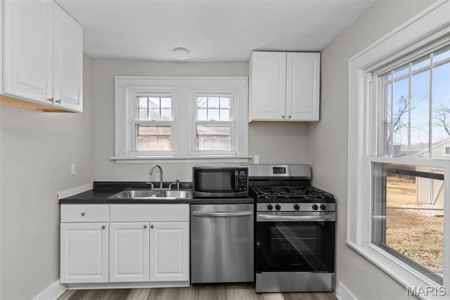 1307 Weleba Ave, Saint Louis, MO 63121 - kitchen featuring stainless steel appliances, white cabinetry, light wood-type flooring, and dark countertops