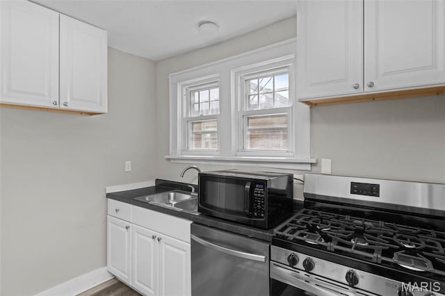 1307 Weleba Ave, Saint Louis, MO 63121 - kitchen with stainless steel appliances, dark countertops, white cabinetry, and wood finished floors