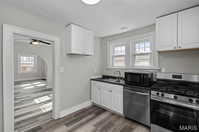 1307 Weleba Ave, Saint Louis, MO 63121 - kitchen featuring stainless steel appliances, wood finished floors, white cabinetry, and dark countertops