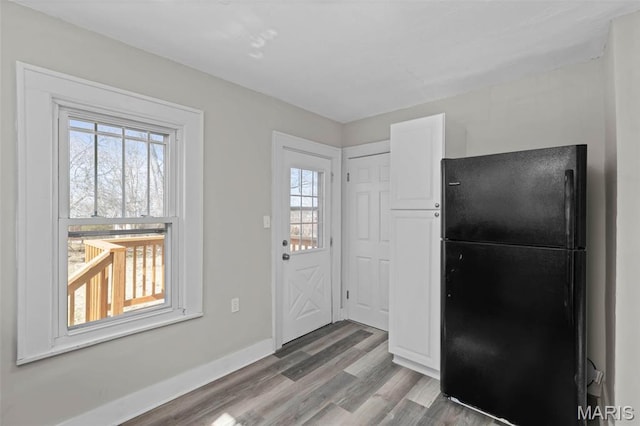 1307 Weleba Ave, Saint Louis, MO 63121 - kitchen with freestanding refrigerator, plenty of natural light, wood finished floors, and white cabinetry