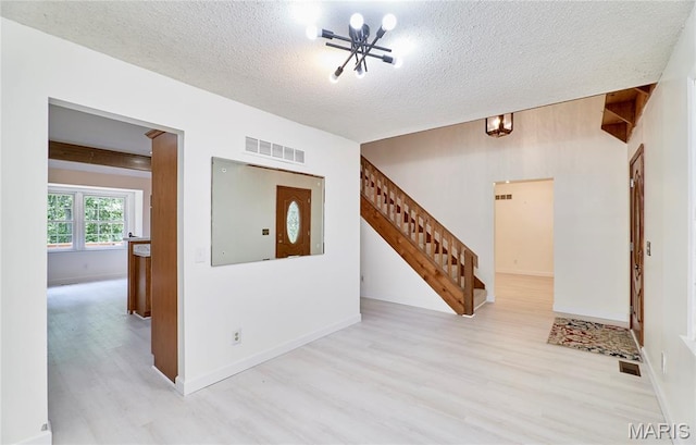 271 Westwood Trl, Foristell, MO 63348 - unfurnished room with wood finished floors, a chandelier, stairs, and a textured ceiling