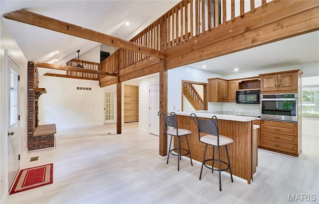 271 Westwood Trl, Foristell, MO 63348 - kitchen featuring oven, black microwave, open floor plan, a kitchen breakfast bar, and high vaulted ceiling