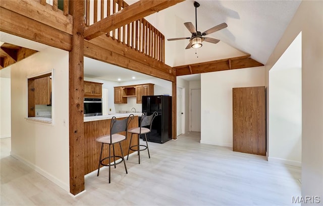 271 Westwood Trl, Foristell, MO 63348 - kitchen with oven, freestanding refrigerator, a kitchen bar, a ceiling fan, and light wood-style flooring