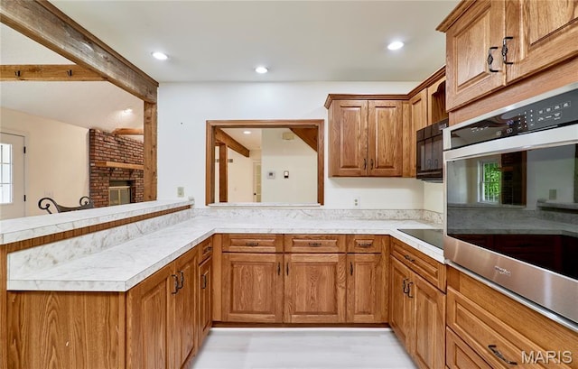 271 Westwood Trl, Foristell, MO 63348 - kitchen with black appliances, brown cabinetry, light countertops, a brick fireplace, and recessed lighting