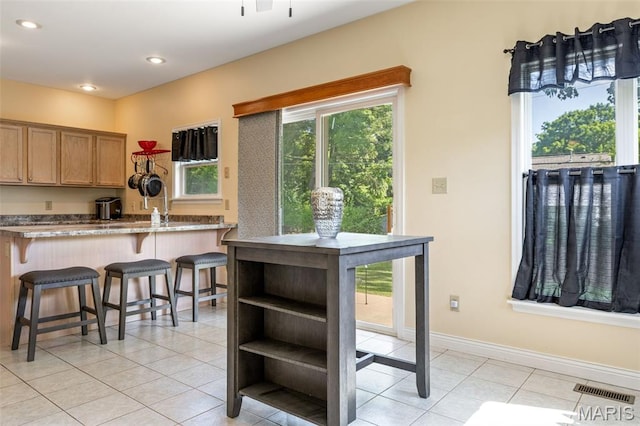 7156 Mardel Ave, Saint Louis, MO 63109 - kitchen with light tile patterned floors, a kitchen bar, recessed lighting, a peninsula, and brown cabinets