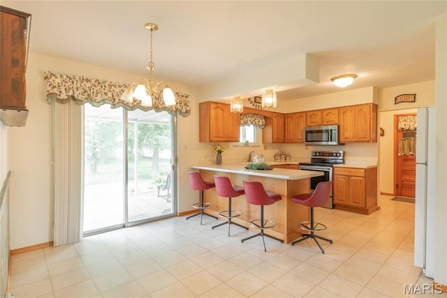 457 Maple Dr, Bethalto, IL 62010 - kitchen with stainless steel appliances, a peninsula, light countertops, a kitchen bar, and a chandelier
