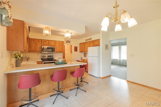 457 Maple Dr, Bethalto, IL 62010 - kitchen featuring stainless steel appliances, a peninsula, light countertops, brown cabinetry, and a chandelier