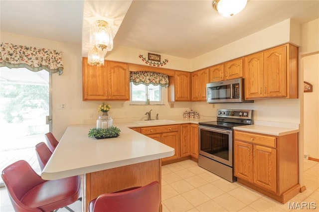 457 Maple Dr, Bethalto, IL 62010 - kitchen with stainless steel appliances, a breakfast bar area, a peninsula, and light countertops