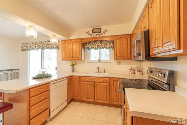 457 Maple Dr, Bethalto, IL 62010 - kitchen featuring appliances with stainless steel finishes, a peninsula, light countertops, light tile patterned flooring, and a kitchen bar