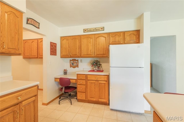 457 Maple Dr, Bethalto, IL 62010 - kitchen with freestanding refrigerator, built in study area, light countertops, brown cabinets, and light tile patterned floors