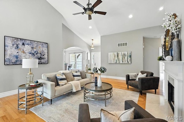 886 Arbor Chase Dr, Wildwood, MO 63021 - living area with arched walkways, ceiling fan, light wood-type flooring, high vaulted ceiling, and a fireplace