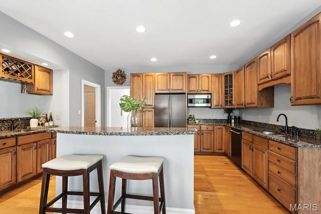 886 Arbor Chase Dr, Wildwood, MO 63021 - kitchen featuring appliances with stainless steel finishes, a breakfast bar area, light wood-style floors, dark stone countertops, and recessed lighting