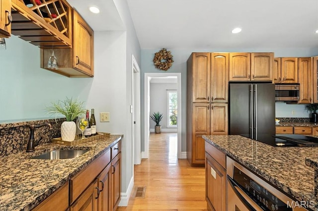 886 Arbor Chase Dr, Wildwood, MO 63021 - kitchen with appliances with stainless steel finishes, light wood-type flooring, dark stone counters, brown cabinetry, and recessed lighting
