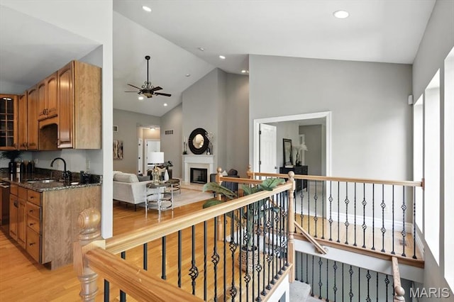 886 Arbor Chase Dr, Wildwood, MO 63021 - kitchen with light wood-style flooring, a ceiling fan, dark stone countertops, brown cabinetry, and a fireplace